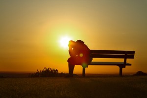 Person sitting on bench at sunset